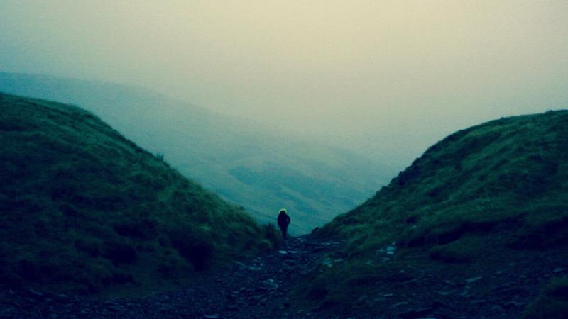 Photograph of hiker on hillside.